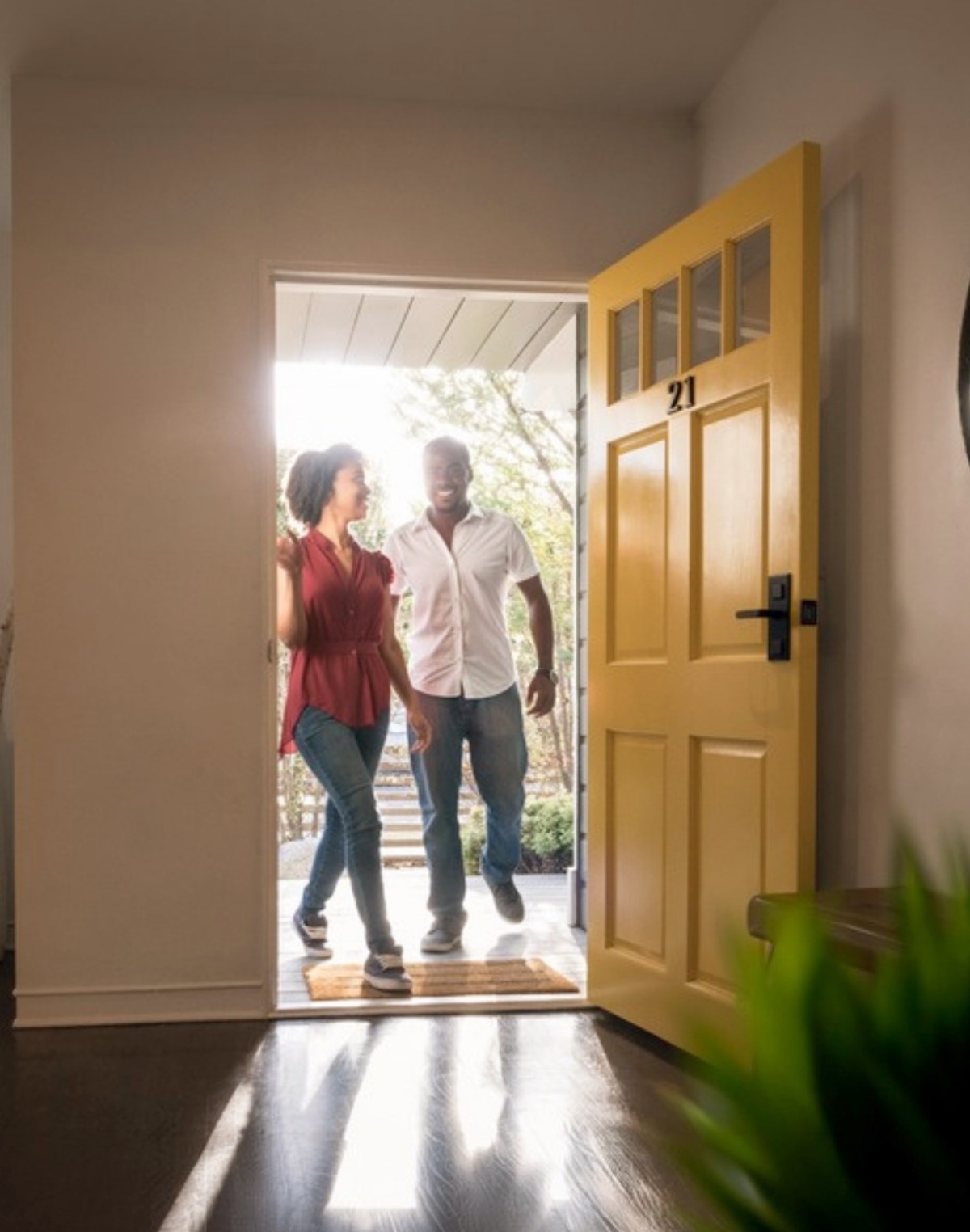 Couple stepping through a yellow front door into their new home