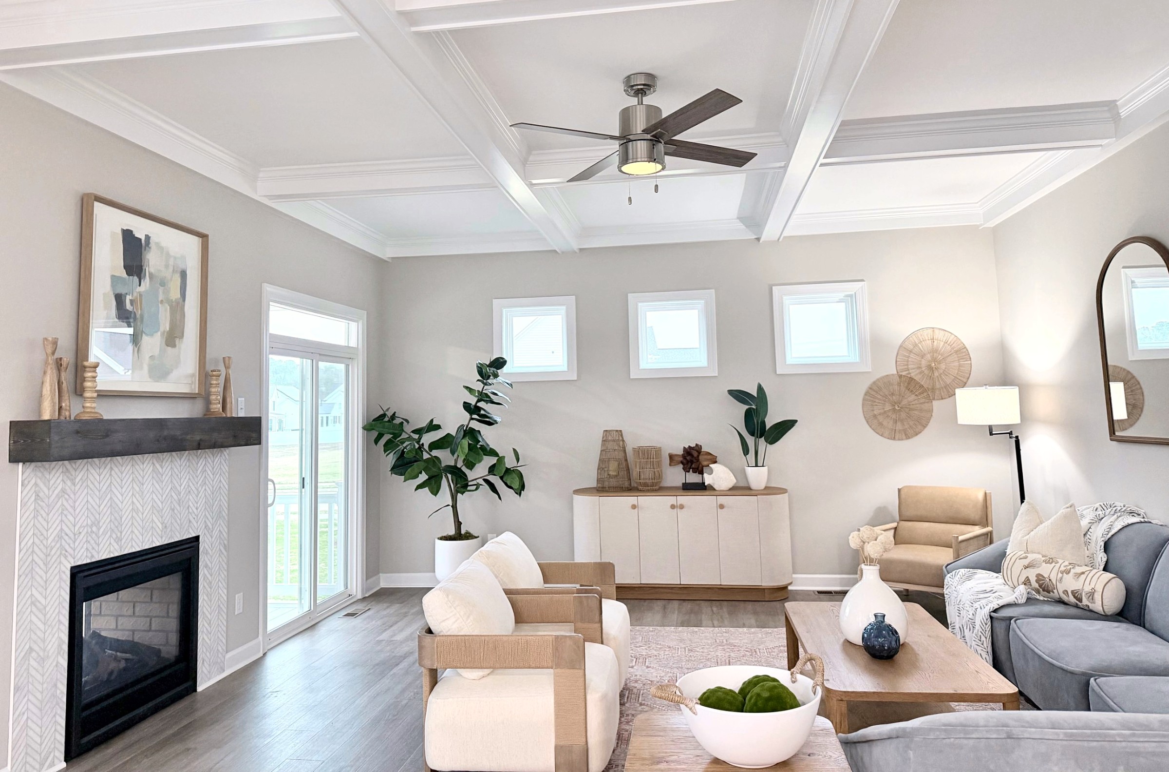 Staged great room with a coffered ceiling, fireplace, and light-filled seating area